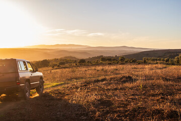 jipe a entrar no enquadramento, na montanha ao p&ocirc;r-do-sol no horizonte