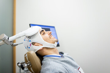 A young Caucasian man between 20 and 30 years old undergoes transcranial magnetic stimulation...