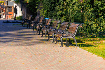 A row of park benches are lined up on a sidewalk
