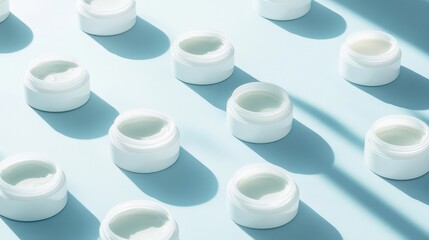 Collection of white cosmetic jars arranged on a pastel background with soft shadows at midday