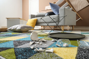 Broken vases on carpet in messy living room after earthquake, closeup