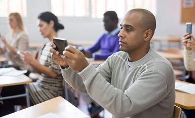 Portrait of focused man using mobile phone during adult education class