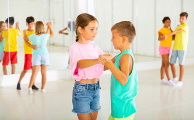 Kids formed pairs and dancing waltz together in studio.