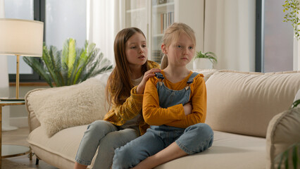 Two little Caucasian kids children siblings daughters girls argument remorseful sister apologizing...
