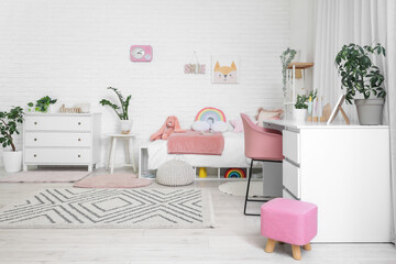 Interior of stylish children's room with bed, study table and drawers