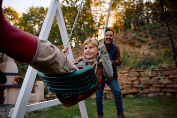 Obraz premium Happy little girl swinging in backyard.