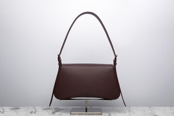 Luxury women's bag on a white background. Dark brown color, leather expensive bag isolated on the marbel in the studio