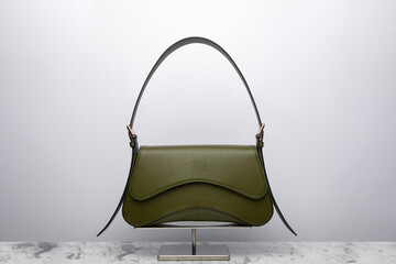 Luxury women's bag on a white background. Dark green color, leather expensive bag isolated on the marbel in the studio