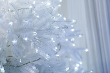 A beautifully decorated frosted white Christmas tree adorned with subtle soft white lights,...