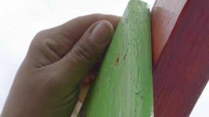 A man’s hands with an electric screwdriver installing screws to build a small garden playground.