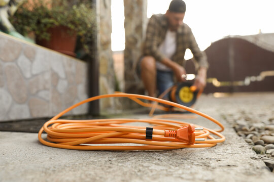 Man with extension cord reel outdoors, selective focus