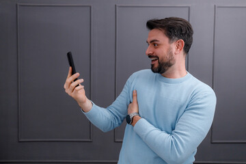 Man smiling while video chatting at home in a modern living space during the day