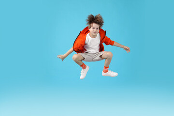 Obraz premium Happy little boy jumping on light blue background