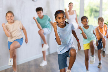 Active preteen boy practicing Hip-hop dance with other children and young trainer during dancing classes
