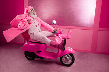 Full length portrait of astonished grandfather wear pink santa outfit hold xmas bag ride bike studio hallway background