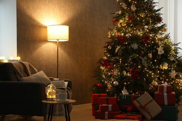 Christmas tree with festive decor, presents, coffee table and armchair in cozy room