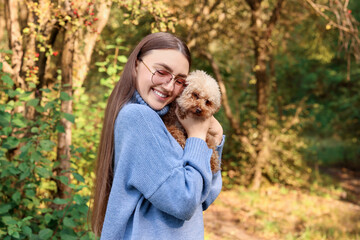 Fototapeta premium Smiling woman with cute dog in autumn park