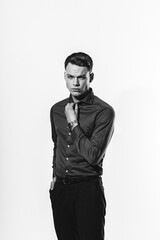 A stylish black and white portrait of a man in a shirt posing on a white cyclorama.