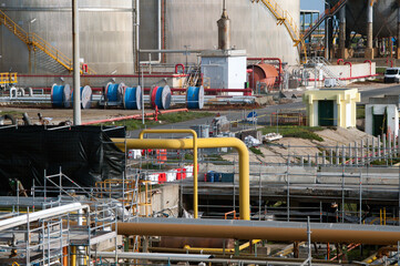 A detailed industrial scene showcasing vibrant yellow pipelines, spools of cable, and other infrastructure elements, representing modern energy systems and engineering precision.