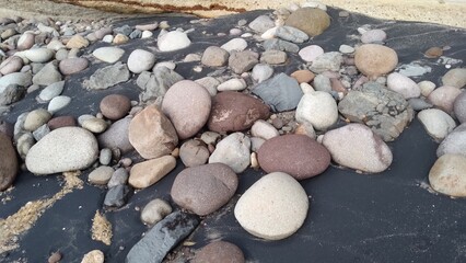 rocks of different sizes and colors on the sand of the beach