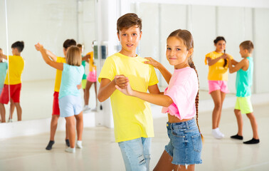 Kids formed pairs and dancing waltz together in studio.