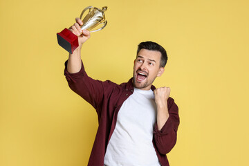 Happy winner with golden trophy cup on yellow background