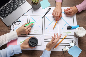 Developing UI design. Designers creating website wireframe on paper at wooden table, top view