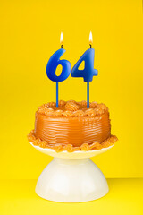 Happy birthday cake with number 64 candle - Card on a yellow background.