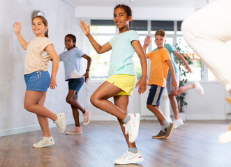 Fototapeta premium Smiling cute african american tween girl visiting group choreography class, learning modern dynamic dances. Concept of active lifestyle of children
