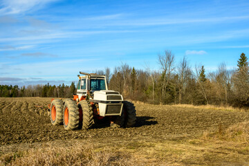 Obraz premium tractor and harrrow on the edge of a recently tilled field in the ottawa valley in fall room for text