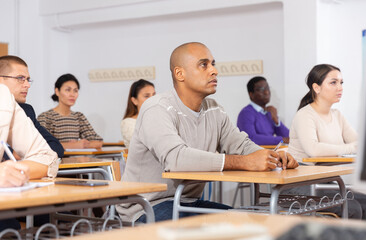 Small group of students attentively listening to lecture in classroom