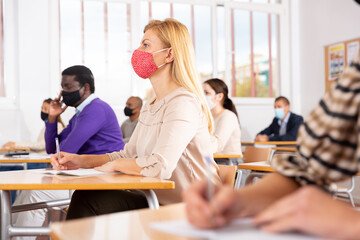 Fototapeta premium Group of adult students in protective masks at lecture at the university