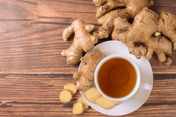 Hot ginger tea with ginger root and slice on wooden table. top view