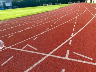 Fototapeta premium Red athletics track featuring crisp white lane markings and numbered lanes 