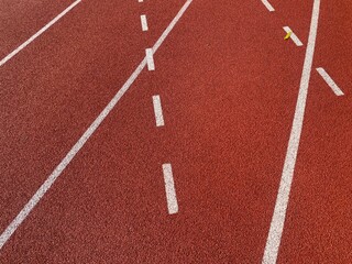 Detailed view of a red running track with lane numbers and white lines
