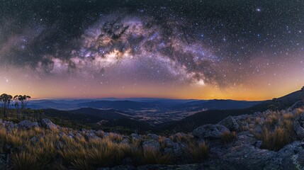 A cluster of twinkling stars over a mountain landscape, with the Milky Way clearly visible in the sky