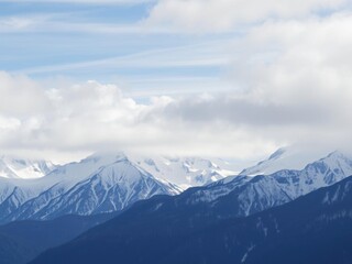 Fototapeta premium A breathtaking view of a snow-capped mountain range with misty clouds hovering above, untouched, calm