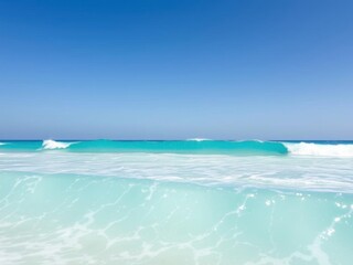 Fototapeta premium Beautiful turquoise waves crashing onto a sandy beach under a clear blue sky, tide, waves
