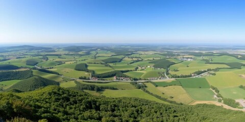 Fototapeta premium A breathtaking panoramic view of a lush, rolling green countryside under a clear blue sky, picturesque, tranquil