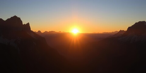 Obraz premium A stunning image of the sun rising over majestic mountains, casting a warm glow on the rugged peaks and creating a peaceful and serene atmosphere, travel, serene