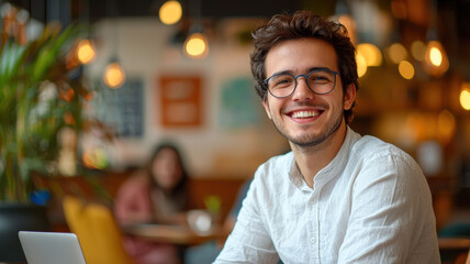 Fototapeta premium A young entrepreneur smiling while focused on working on a laptop in a bright co-working space, featuring a minimalistic design with clean lines and modern furniture.