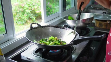 Slow motion footage of cooking, stir-frying vegetables in a pan in the kitchen. Fresh, organic green vegetables that help maintain the body. Garden vegetables. Cooking with heat. Video menu for lunch 