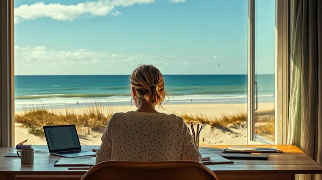 Woman working at desk with ocean view from beachfront location during a sunny day