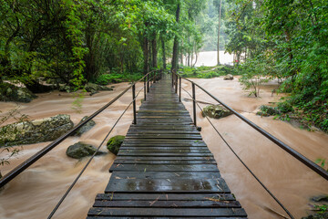 Obraz premium The wooden bridge spans a stream with rushing waters. This bridge is located at Sri Dit Waterfall, Khao Kho District, Phetchabun Province, Thailand