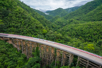 An aerial view of Phor Khun Pha Muang Bridge, or Huai Tong Bridge in Phetchabun, showcases its majestic span through a high mountain pass, connecting northern and northeastern Thailand