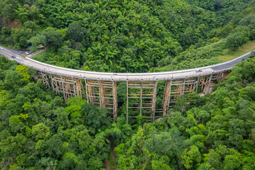 An aerial view of Phor Khun Pha Muang Bridge, or Huai Tong Bridge in Phetchabun, showcases its majestic span through a high mountain pass, connecting northern and northeastern Thailand