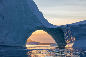 View of sunset through an arch of a huge floating iceberg, Greenland © PetraJPhoto