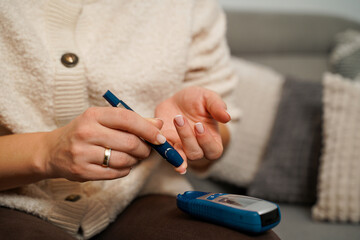 Obraz premium Unrecognizable woman using needle pen to measure blood sugar with glucometer 