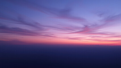 Fototapeta premium Dusk sky with gradient purple and blue hues, soft clouds drifting across the horizon, gradient sky, twilight scene., serene atmosphere, outdoor scenery, soft clouds