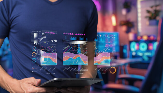 Young professional interacting with futuristic digital data visualization on tablet screen in modern workspace with colorful background decorations